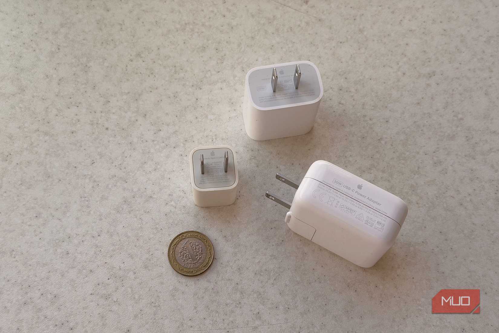 Apple charging blocks, including the original cube, beside a coin for scale.