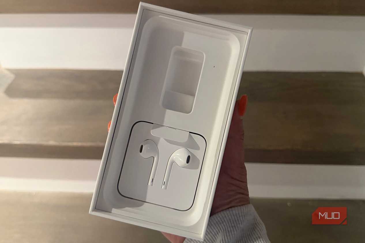 A hand holding an old iPhone box showing the EarPods.