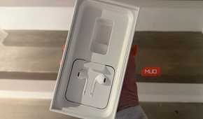 A hand holding an old iPhone box showing the EarPods.