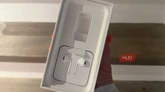 A hand holding an old iPhone box showing the EarPods.