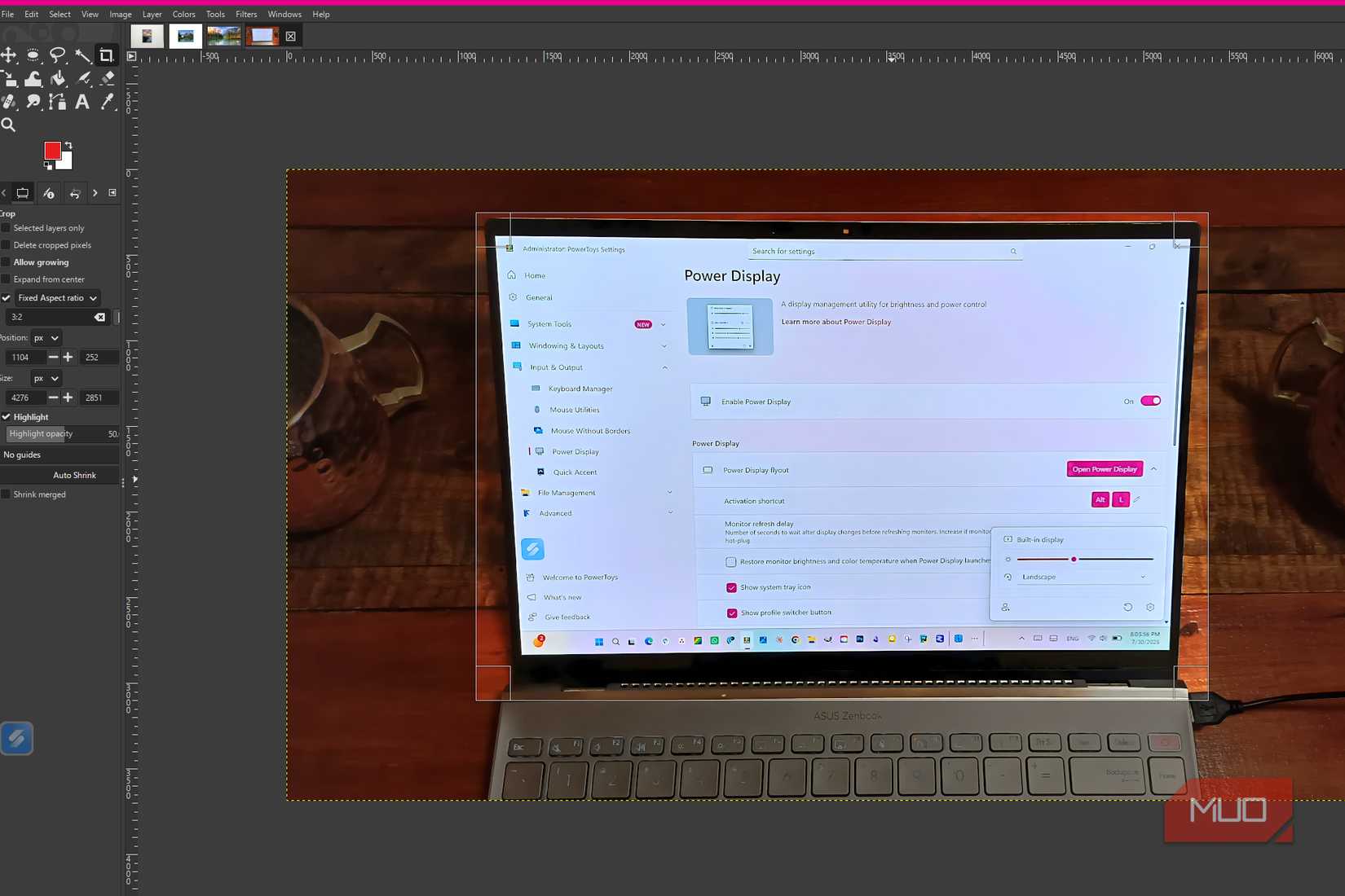 GIMP showing the Crop tool with a crop box drawn around the laptop screen in a photo