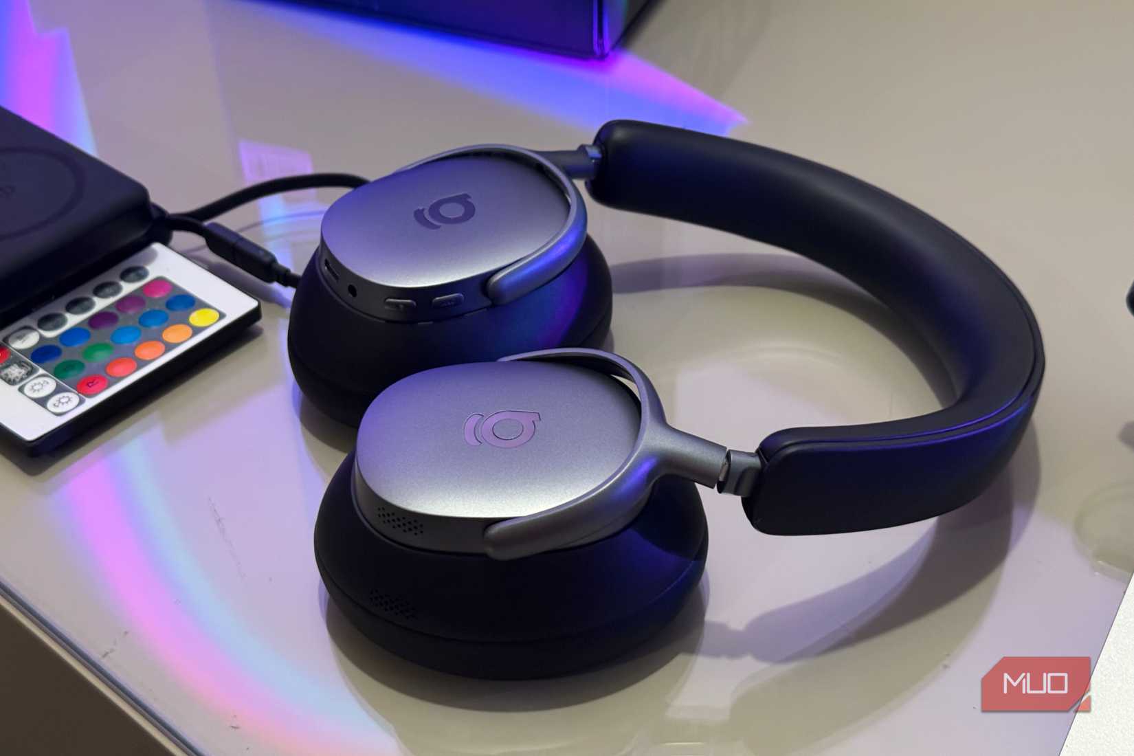 Headphones on table next to color-changing LED remote and charging cable