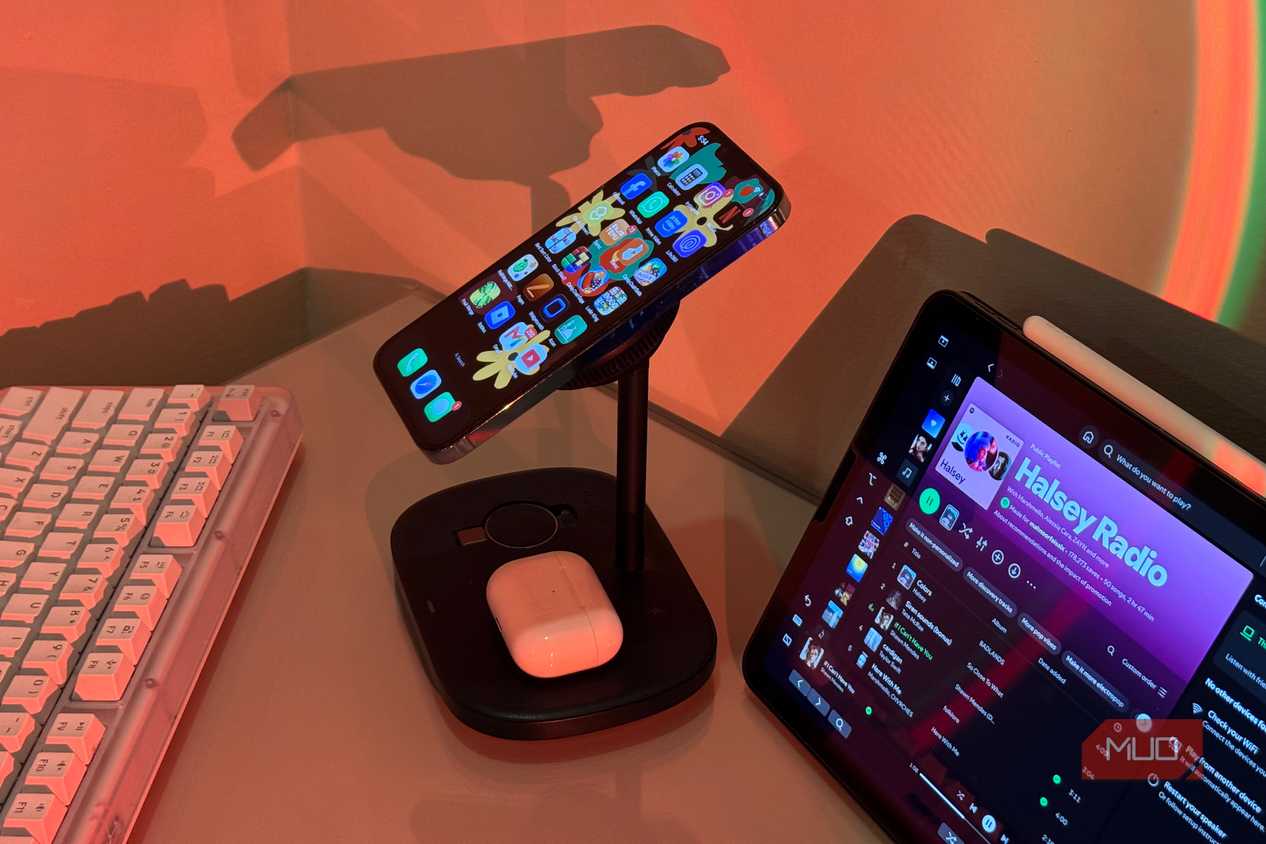 iPhone tilted on Baseus stand with AirPods and iPad Spotify