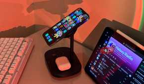 iPhone tilted on Baseus stand with AirPods and iPad Spotify
