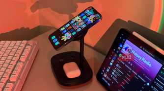 iPhone tilted on Baseus stand with AirPods and iPad Spotify