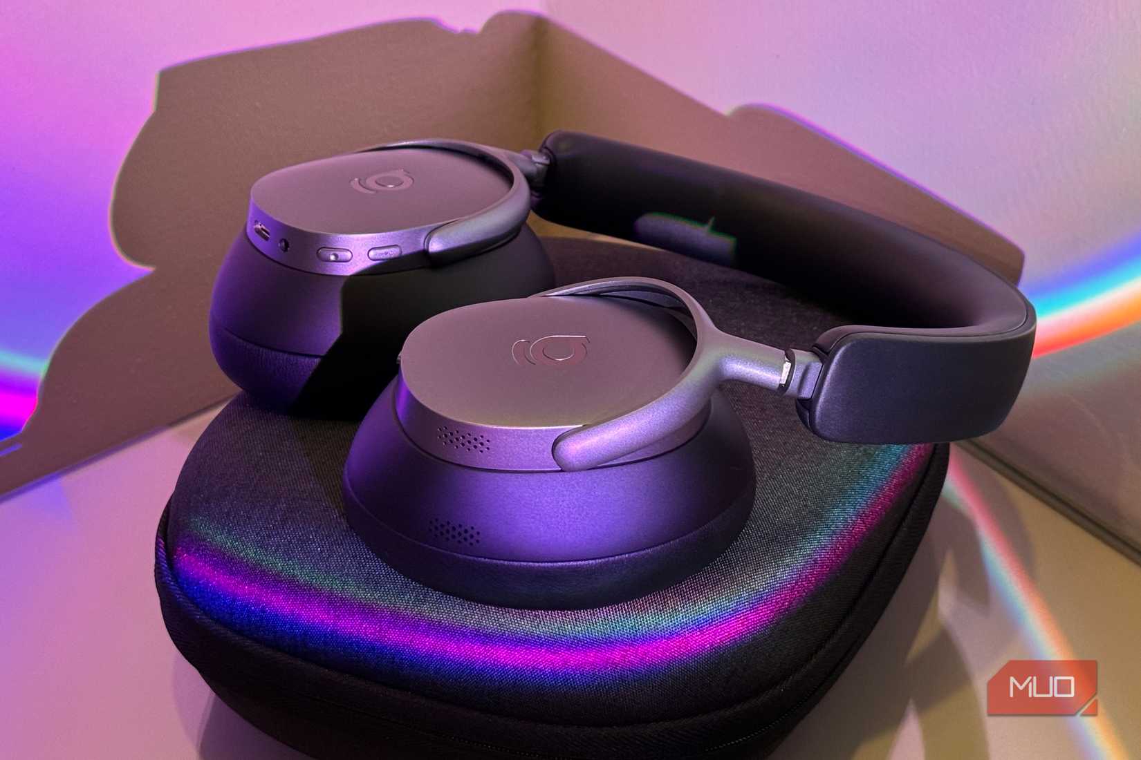Purple-toned headphones on iridescent case, close on control buttons and charging port