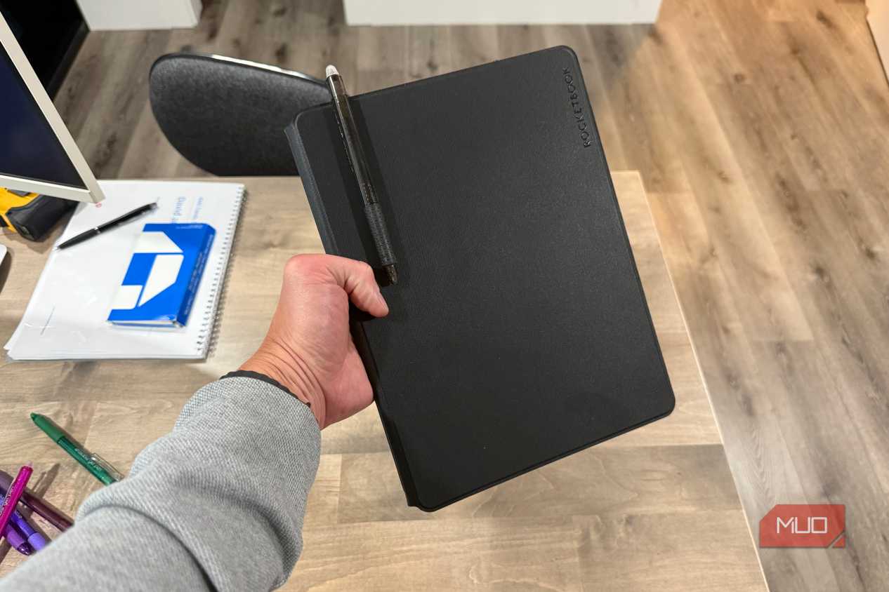 rocketbook pro 2.0 closed held in hand with pen in holder above desk