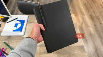 rocketbook pro 2.0 closed held in hand with pen in holder above desk