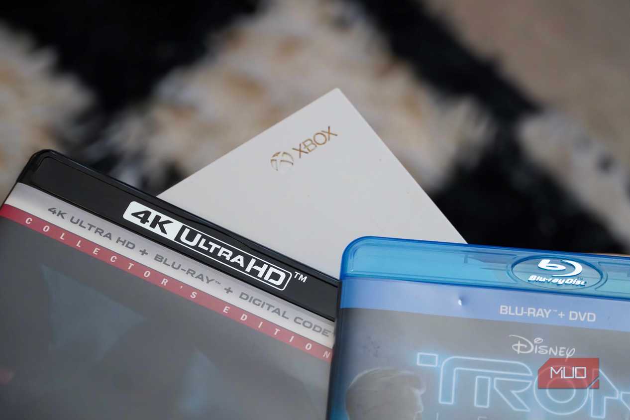 4K UHD and Blu-ray disc cases by the Xbox logo on a One S console.