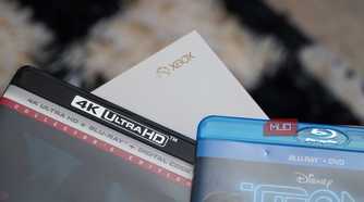 4K UHD and Blu-ray disc cases by the Xbox logo on a One S console.