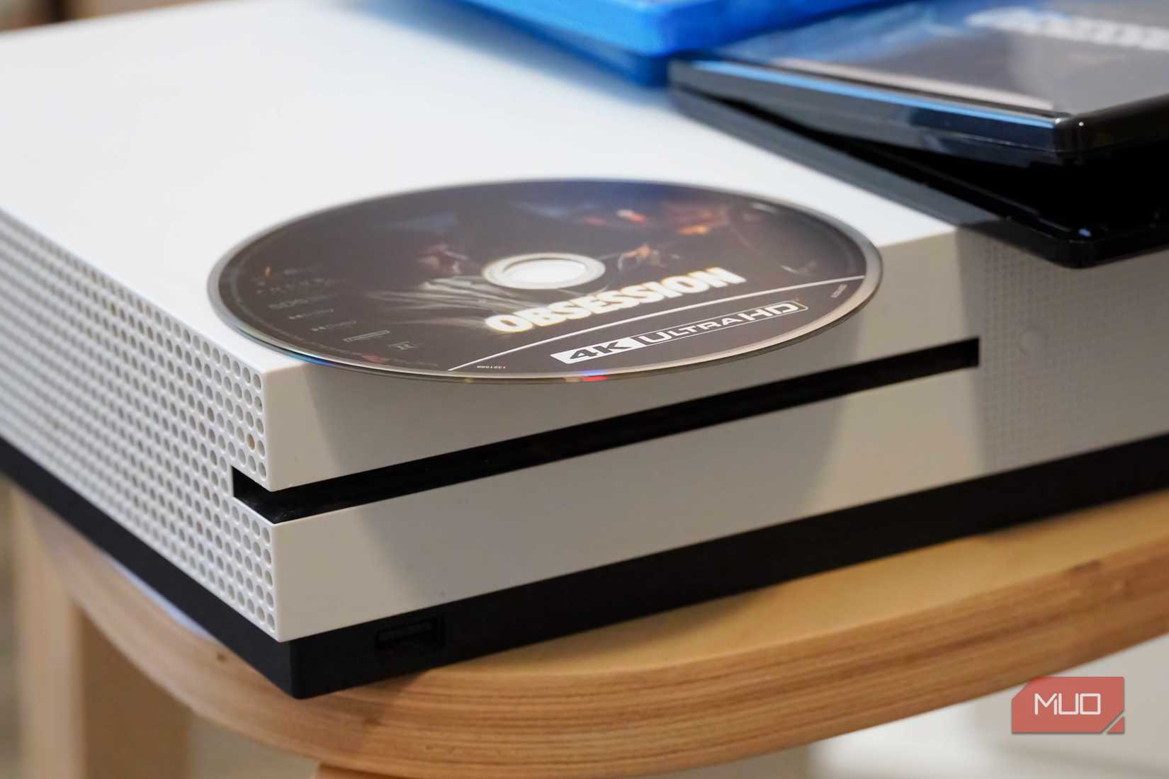 A 4K UHD disc on top of an Xbox One S.