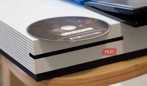 A 4K UHD disc on top of an Xbox One S.