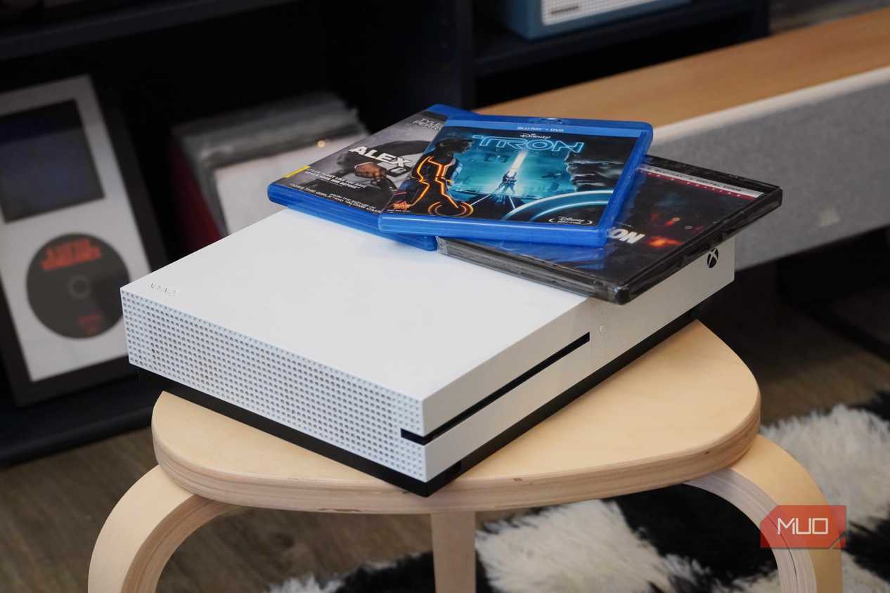 An angled view of the Xbox One S with Blu-ray discs on top.