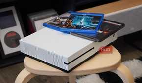 An angled view of the Xbox One S with Blu-ray discs on top.
