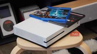 An angled view of the Xbox One S with Blu-ray discs on top.