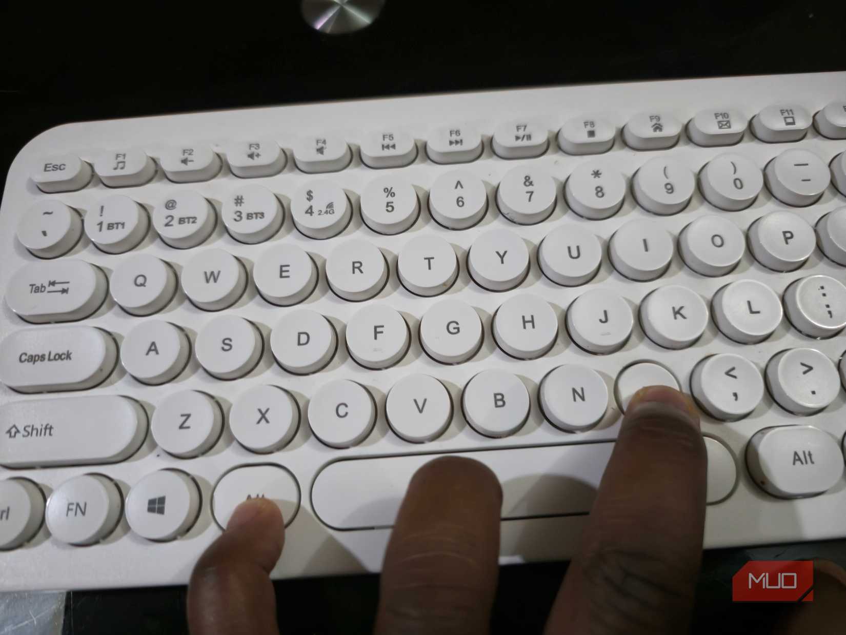 A hand pressing the Alt and M keys on a Windows keyboard