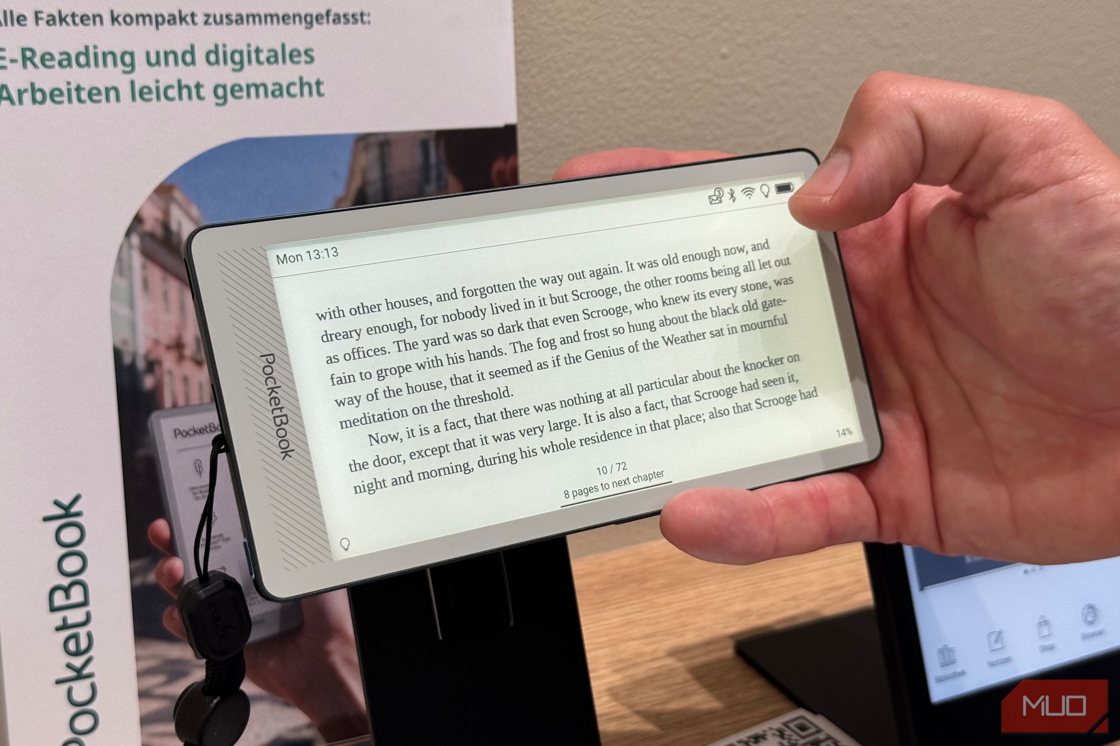 Hand holding a PocketBook Q sideways, reading A Christmas Carol in landscape mode
