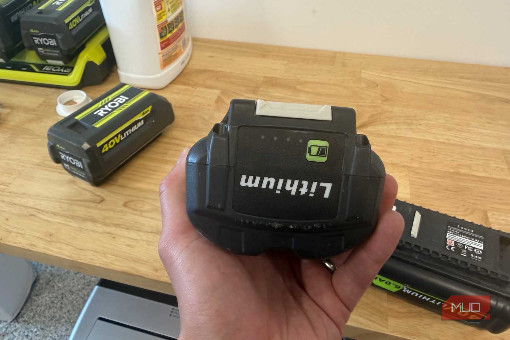 hand holding off-brand ryobi 40V battery with genuine ryobi battery in background