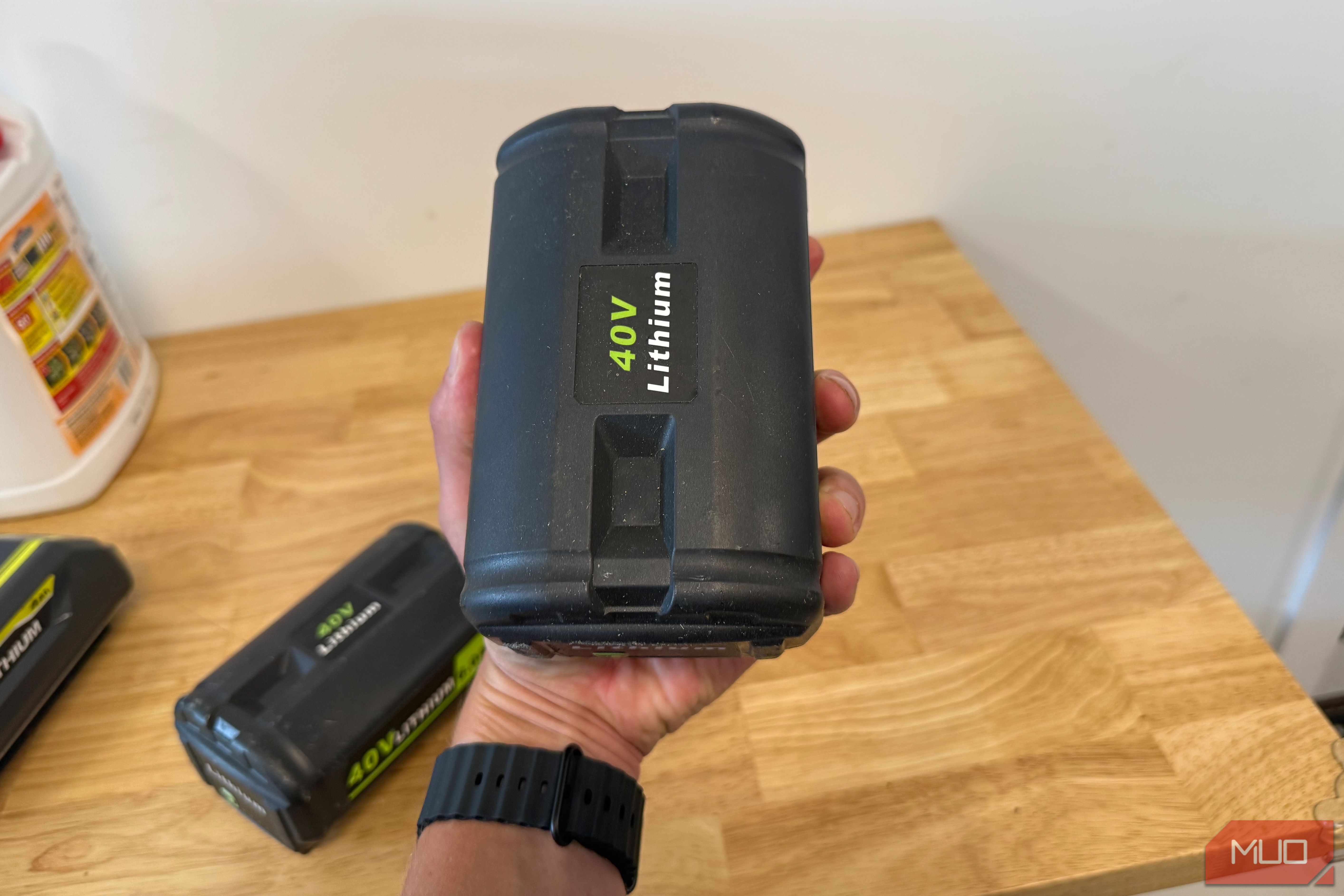 hand holding off-brand ryobi 40V lithium battery upright over workbench