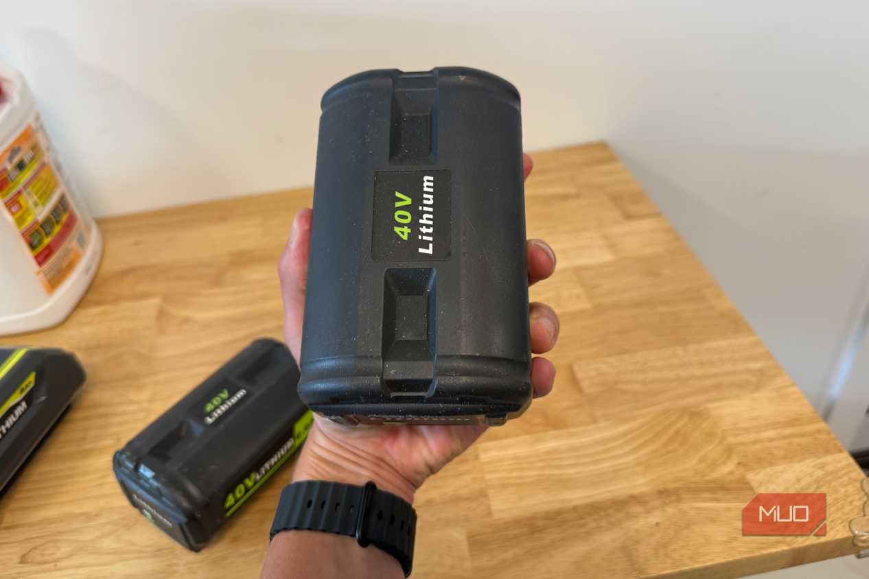 hand holding off-brand ryobi 40V lithium battery upright over workbench