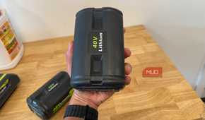 hand holding off-brand ryobi 40V lithium battery upright over workbench