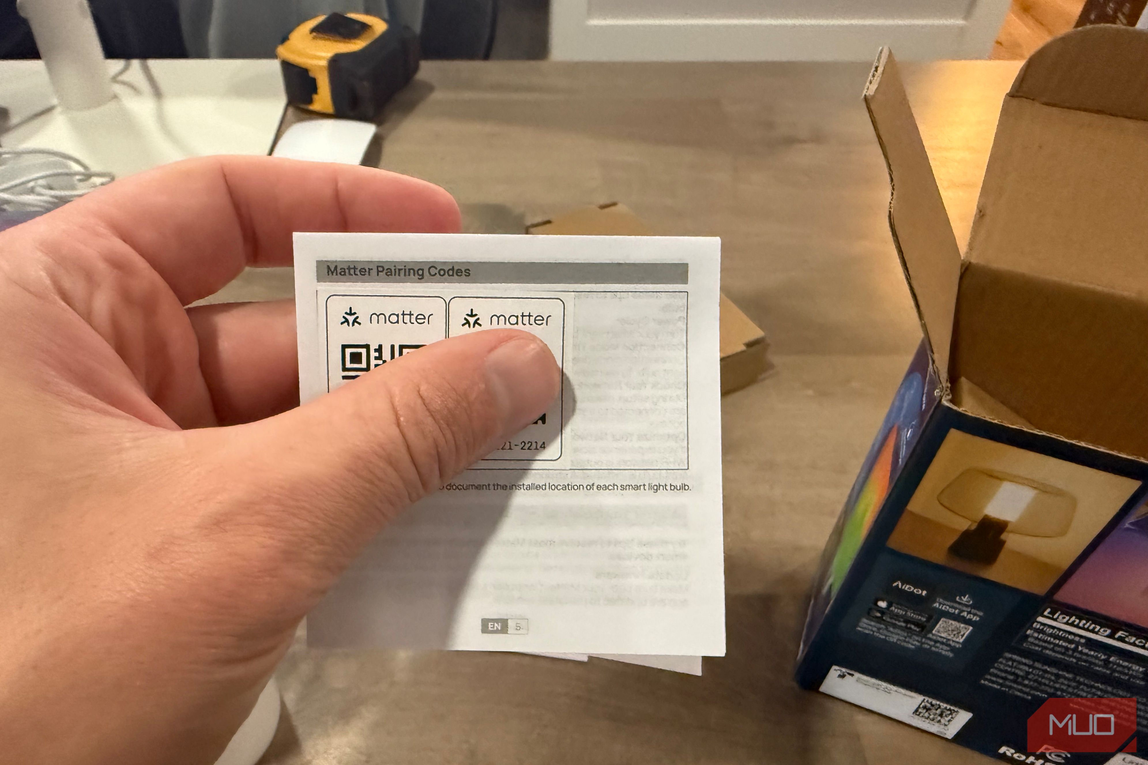 Hand holding the Matter pairing codes card from the packaging