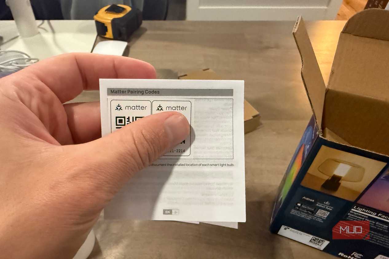 Hand holding the Matter pairing codes card from the packaging