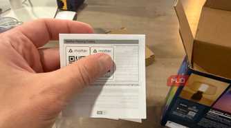 Hand holding the Matter pairing codes card from the packaging