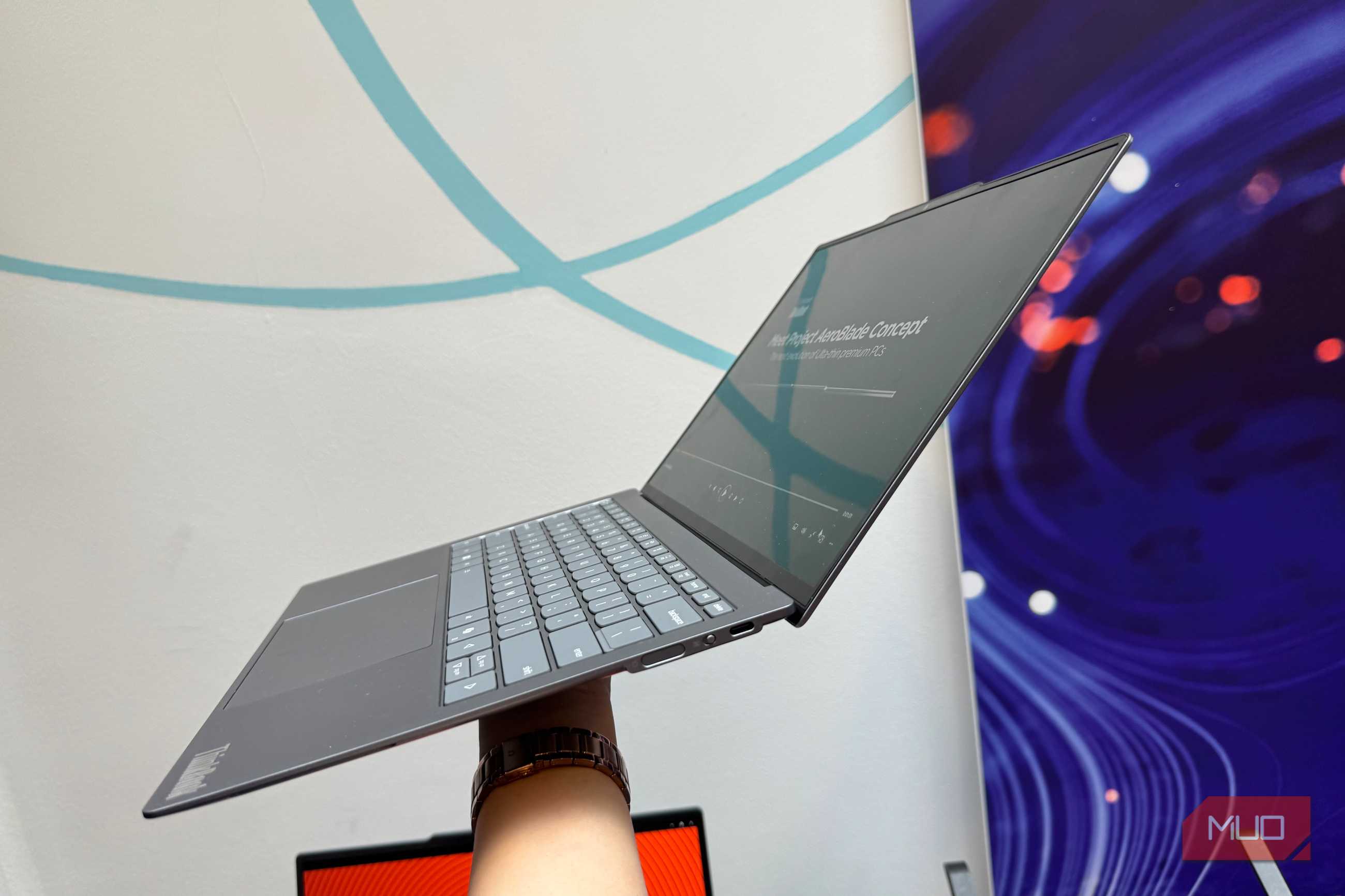 Hand holding up a thin ThinkPad showing the Project AeroBlade Concept slide