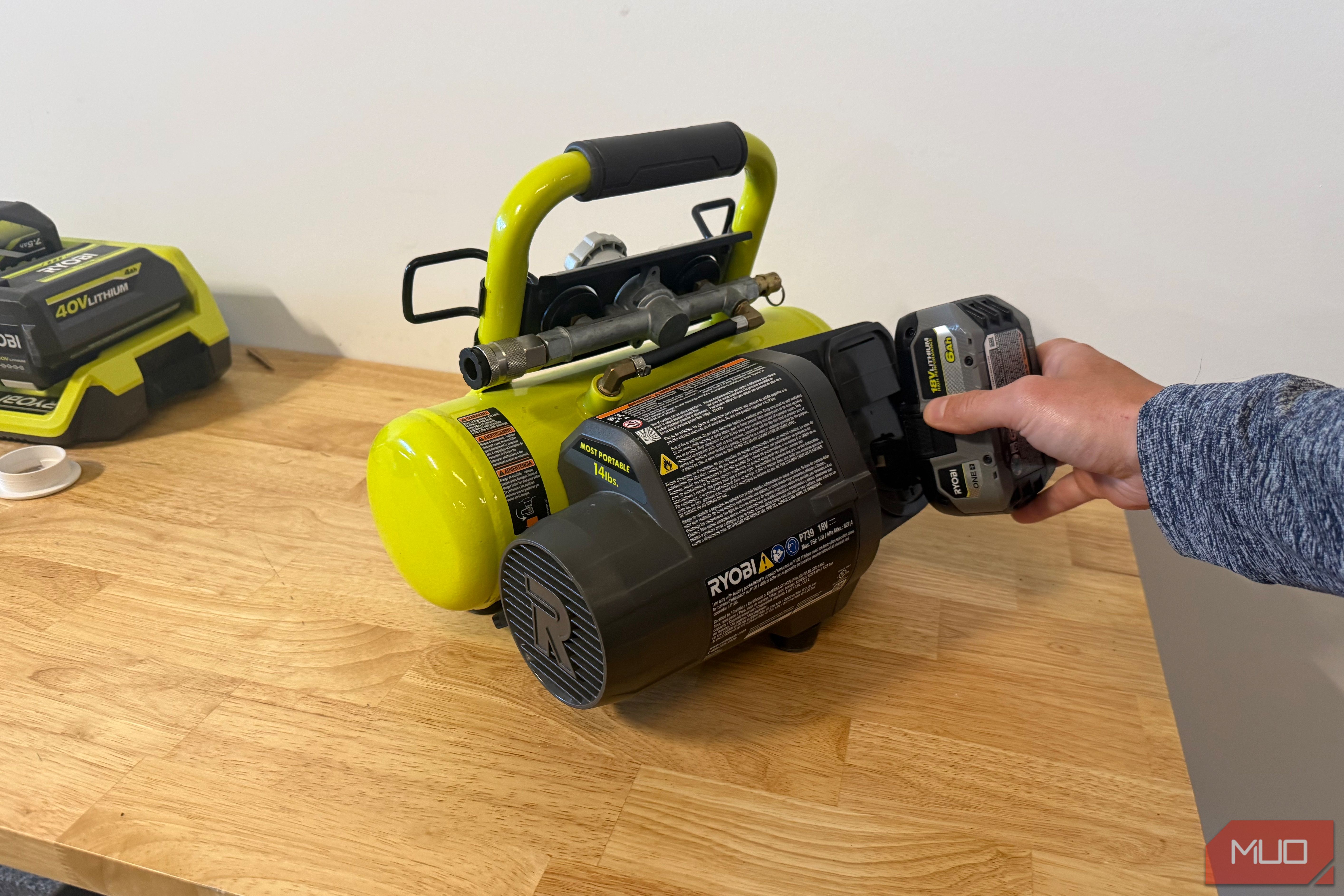Hand inserting 18V battery into Ryobi portable compressor