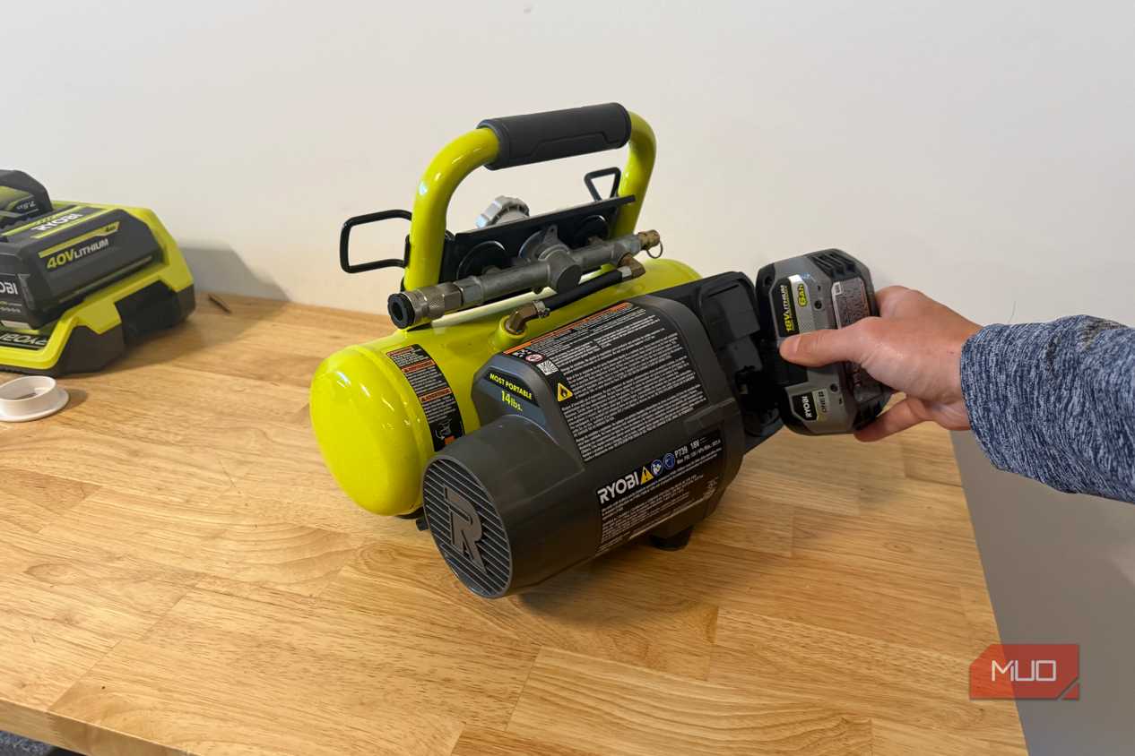 Hand inserting 18V battery into Ryobi portable compressor