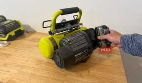 Hand inserting 18V battery into Ryobi portable compressor