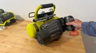 Hand inserting 18V battery into Ryobi portable compressor