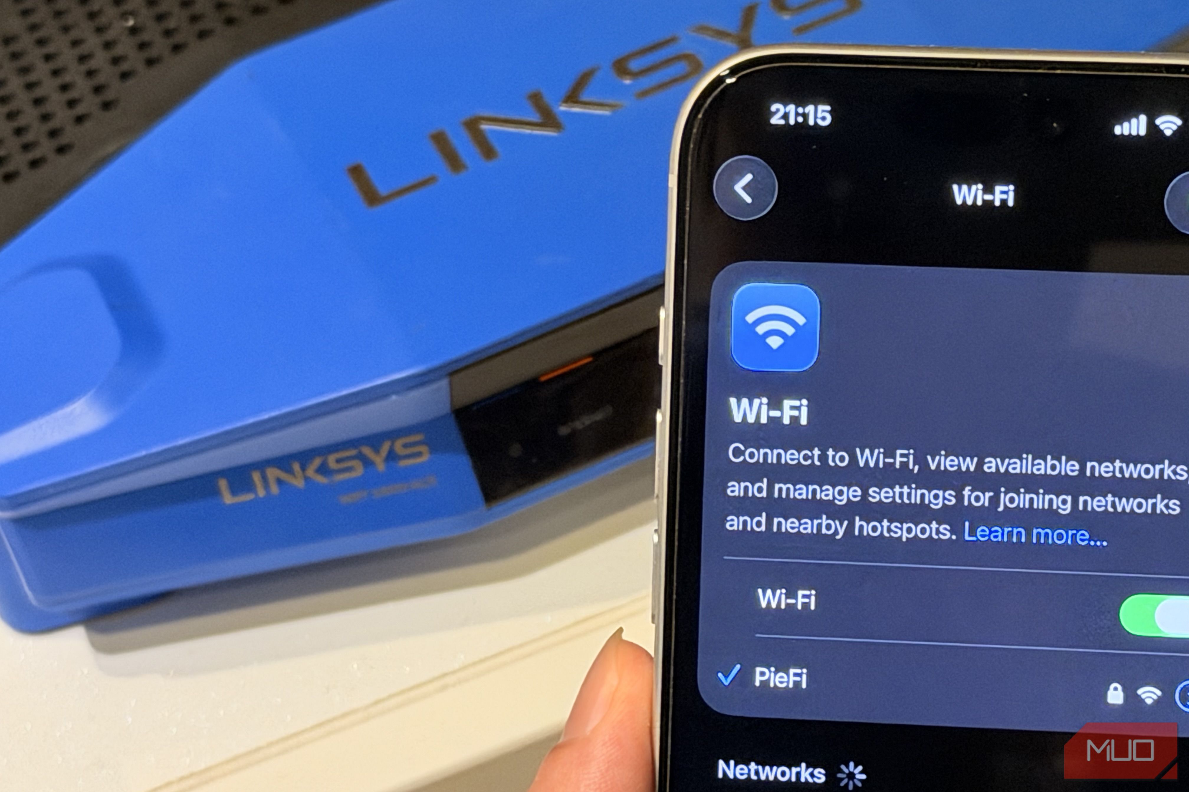 Phone showing full Wi-Fi bar at full signal with a Linksys router in the background