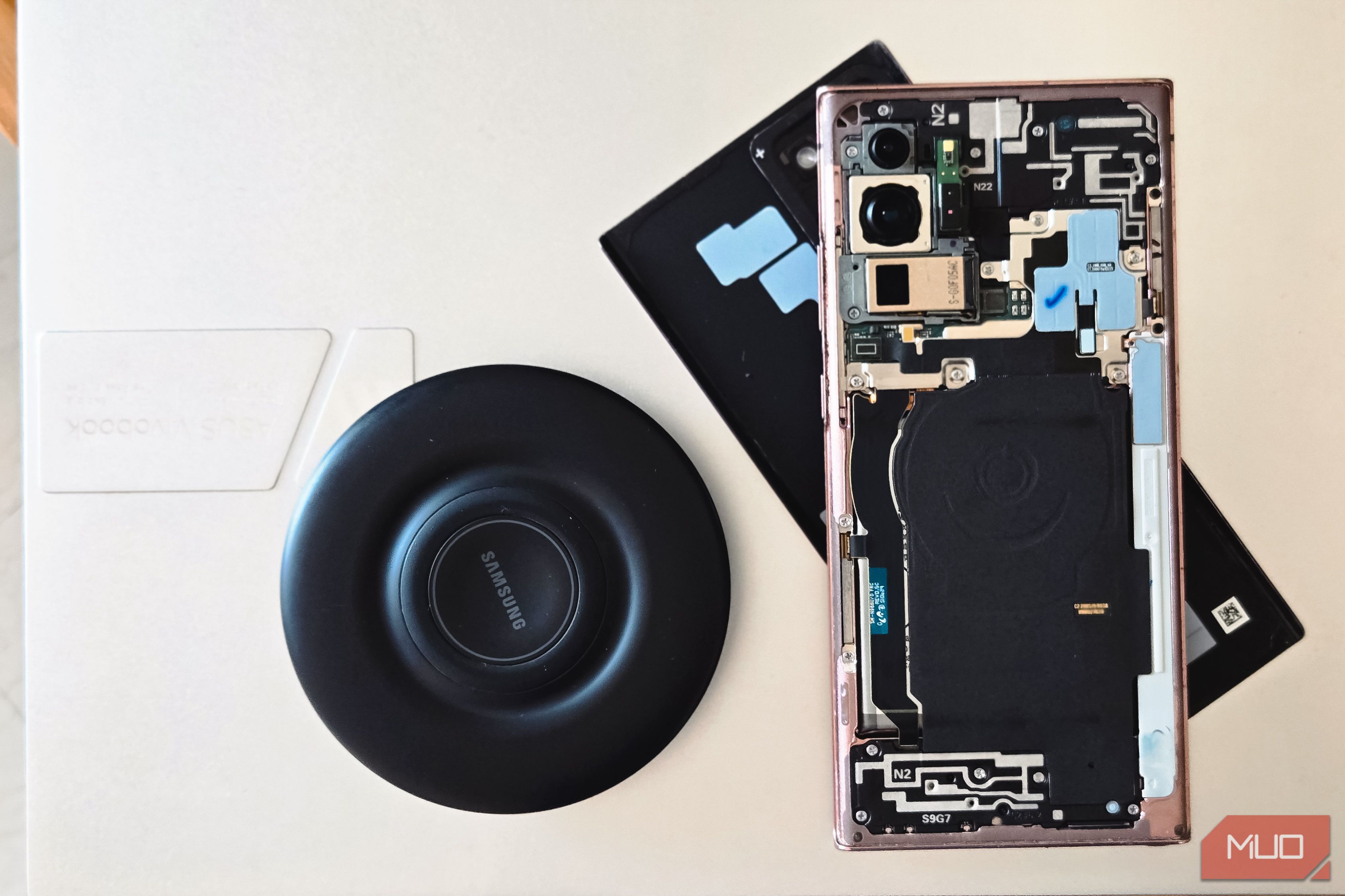 samsung galaxy phone disassembled showing internal components and back cover beside a wireless