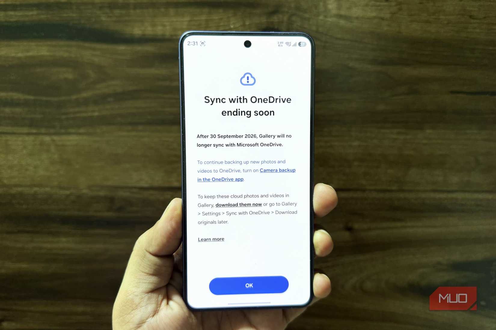 Samsung phone in hand showing OneDrive integration notice