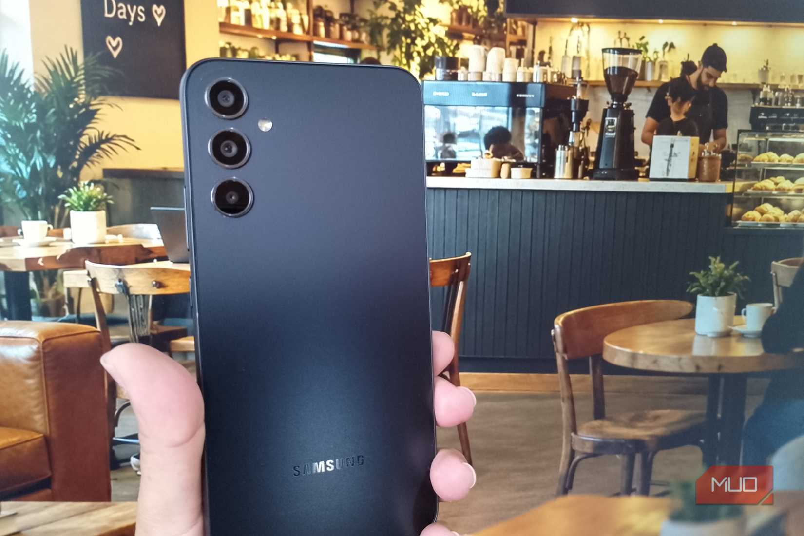 A Galaxy phone held against wallpaper of a coffee shop