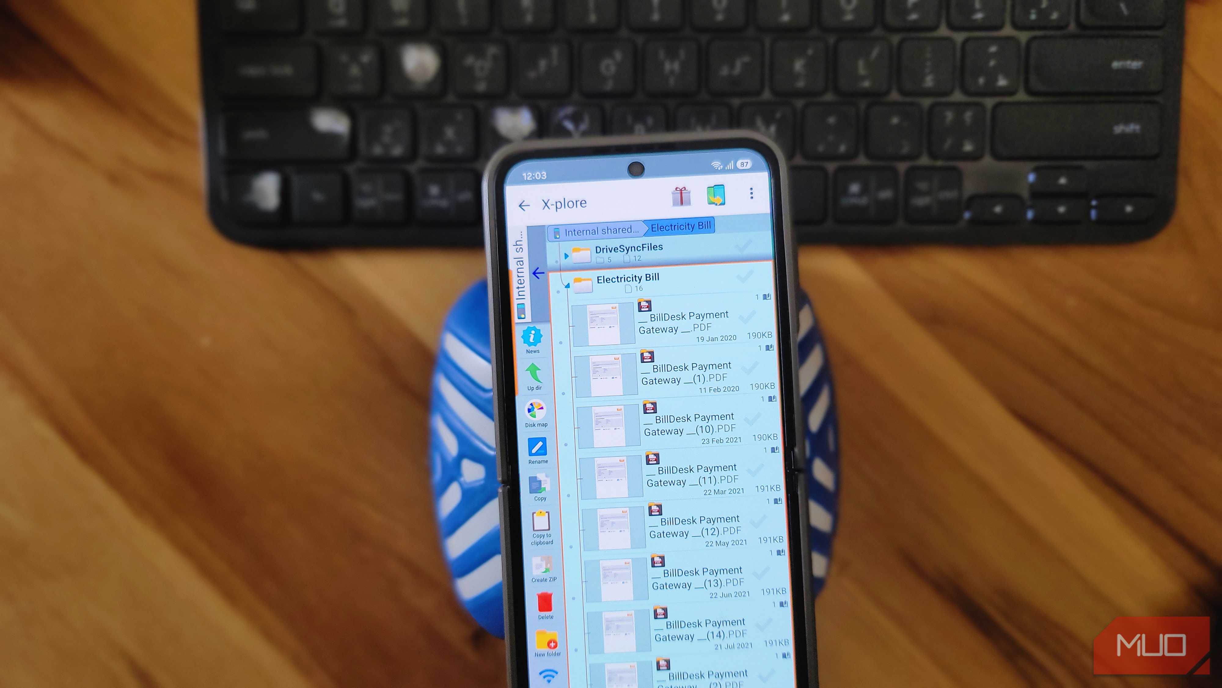 phone file manager showing electricity bill billdesk payment pdfs on wooden desk