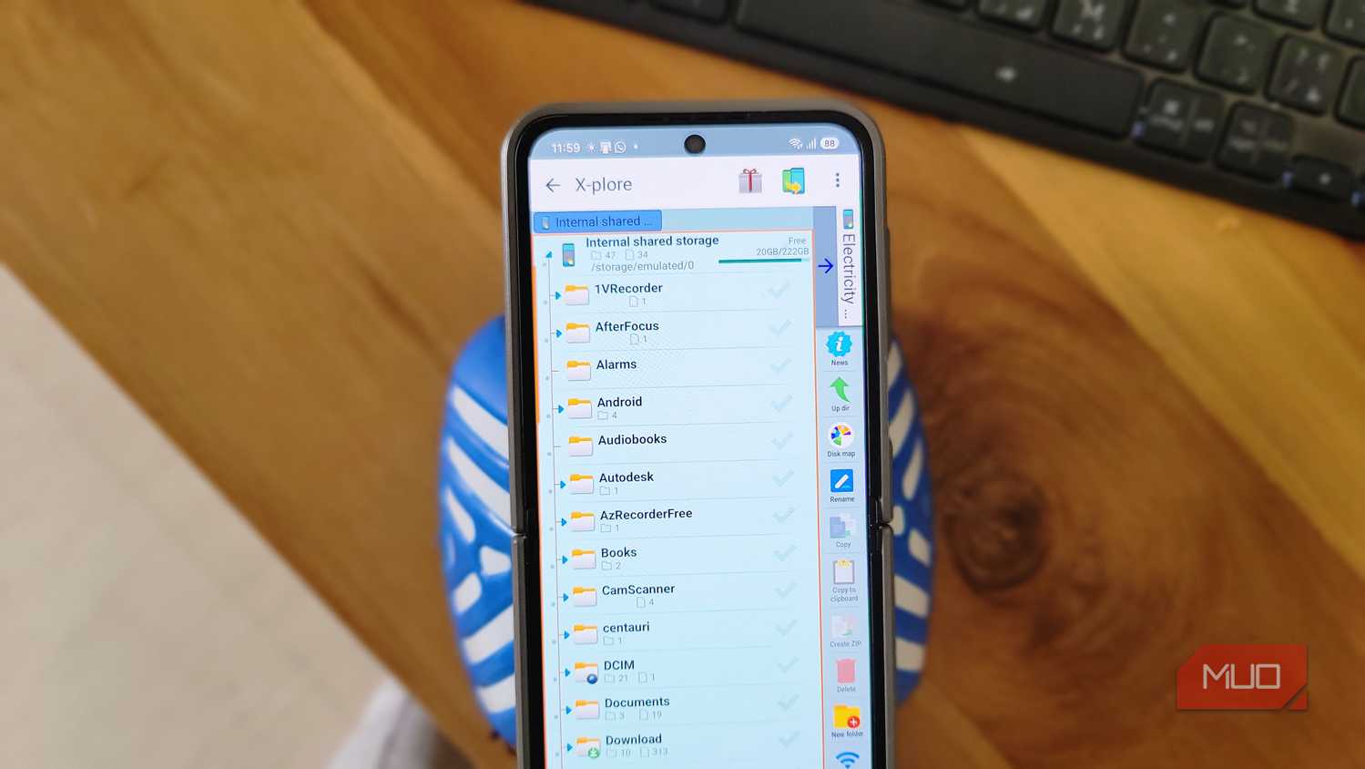 phone showing x plore file manager browsing internal shared storage folders on wooden desk