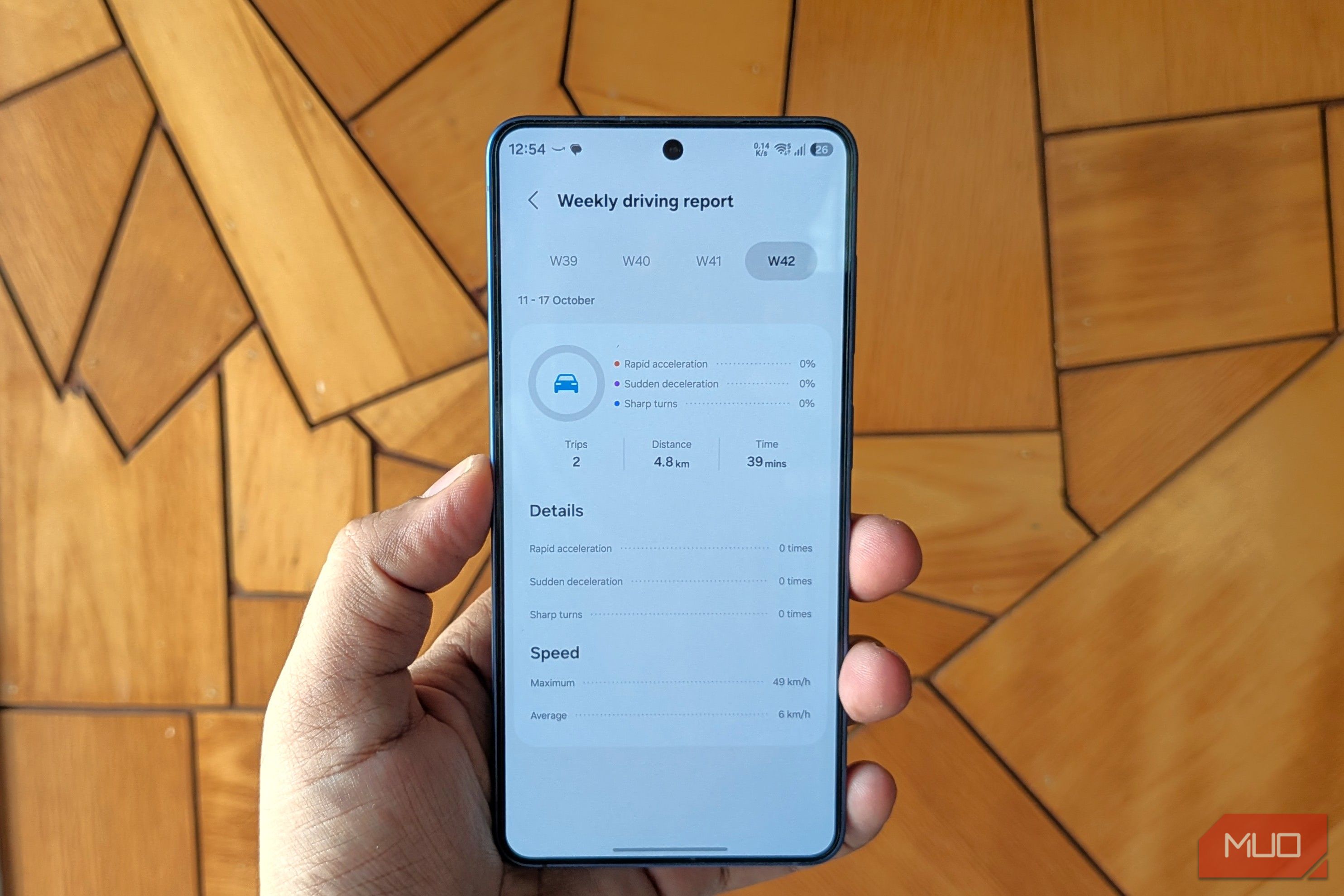 Samsung phone in hand showing driving report from One UI 9