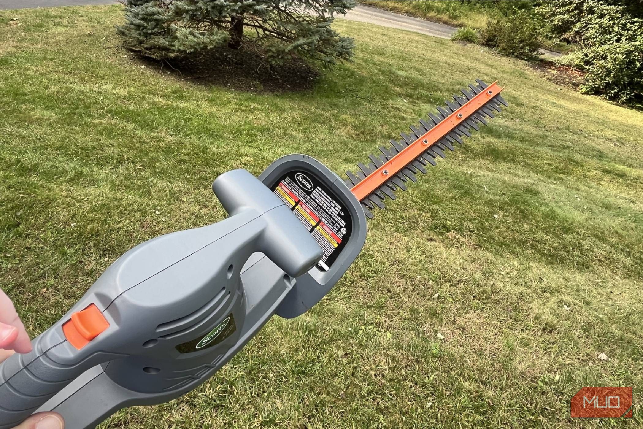 Scotts Corded Hedge Trimmer being held up over grass