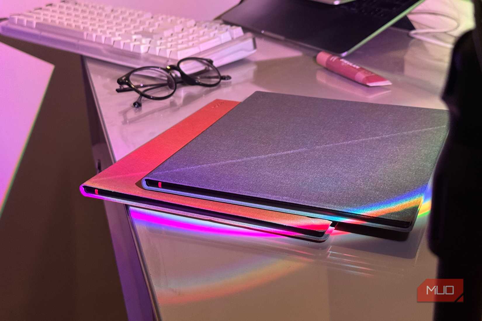 Two Boox Note Air6 C tablets in fabric folio cases stacked next to a keyboard and glasses-1