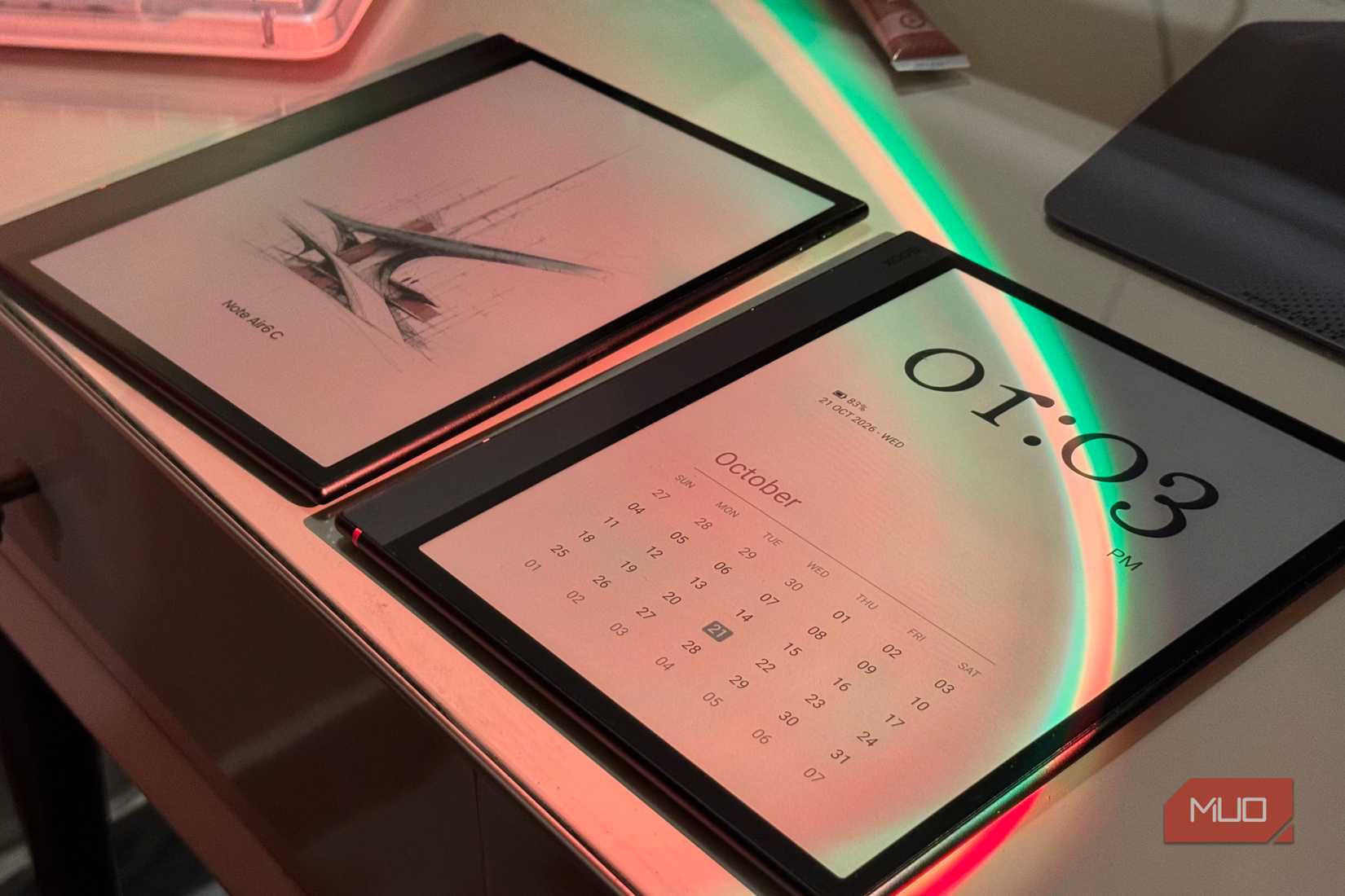 Two Boox Note Air6 C tablets side by side, one on the boot logo and one on a clock screensaver