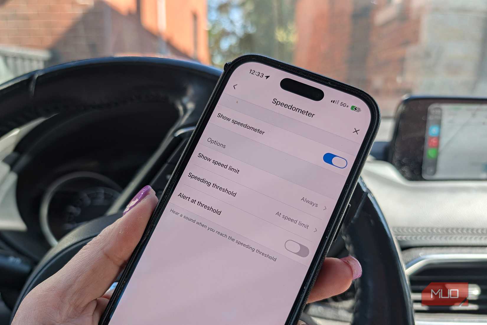 An iPhone in a car showing a close-up of the Speedometer settings in Waze.